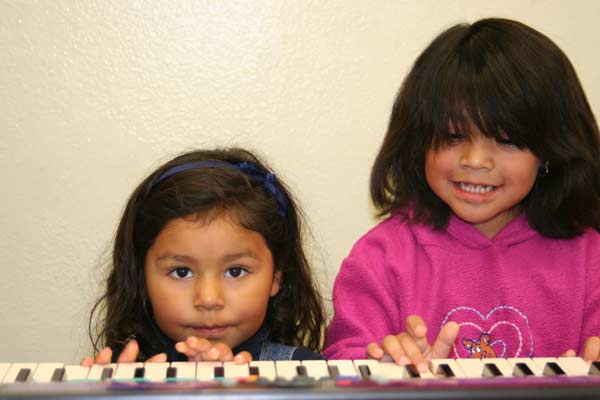 Beautiful little girls playing the keyboard together